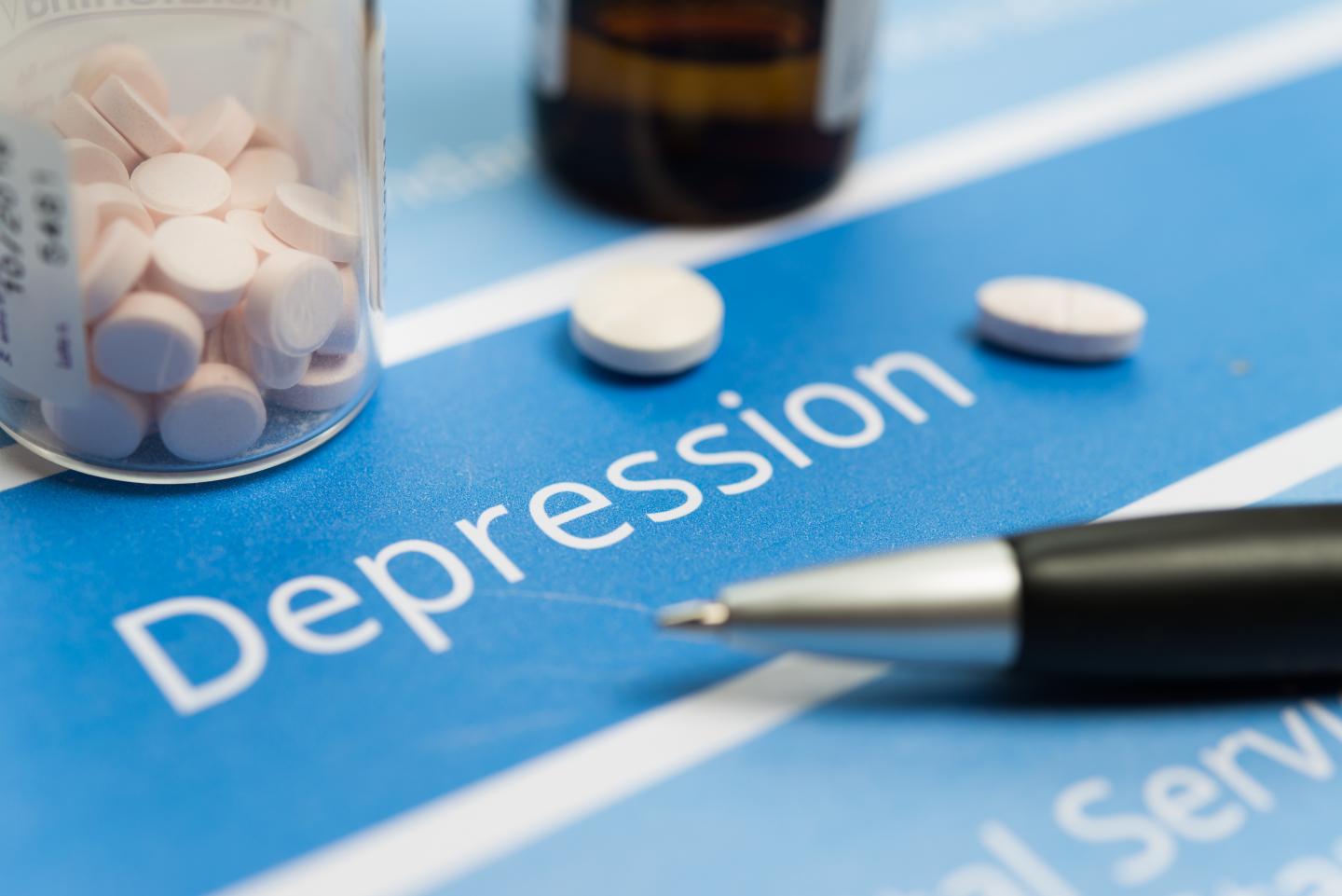 bottle of pills sit atop a page reading depression