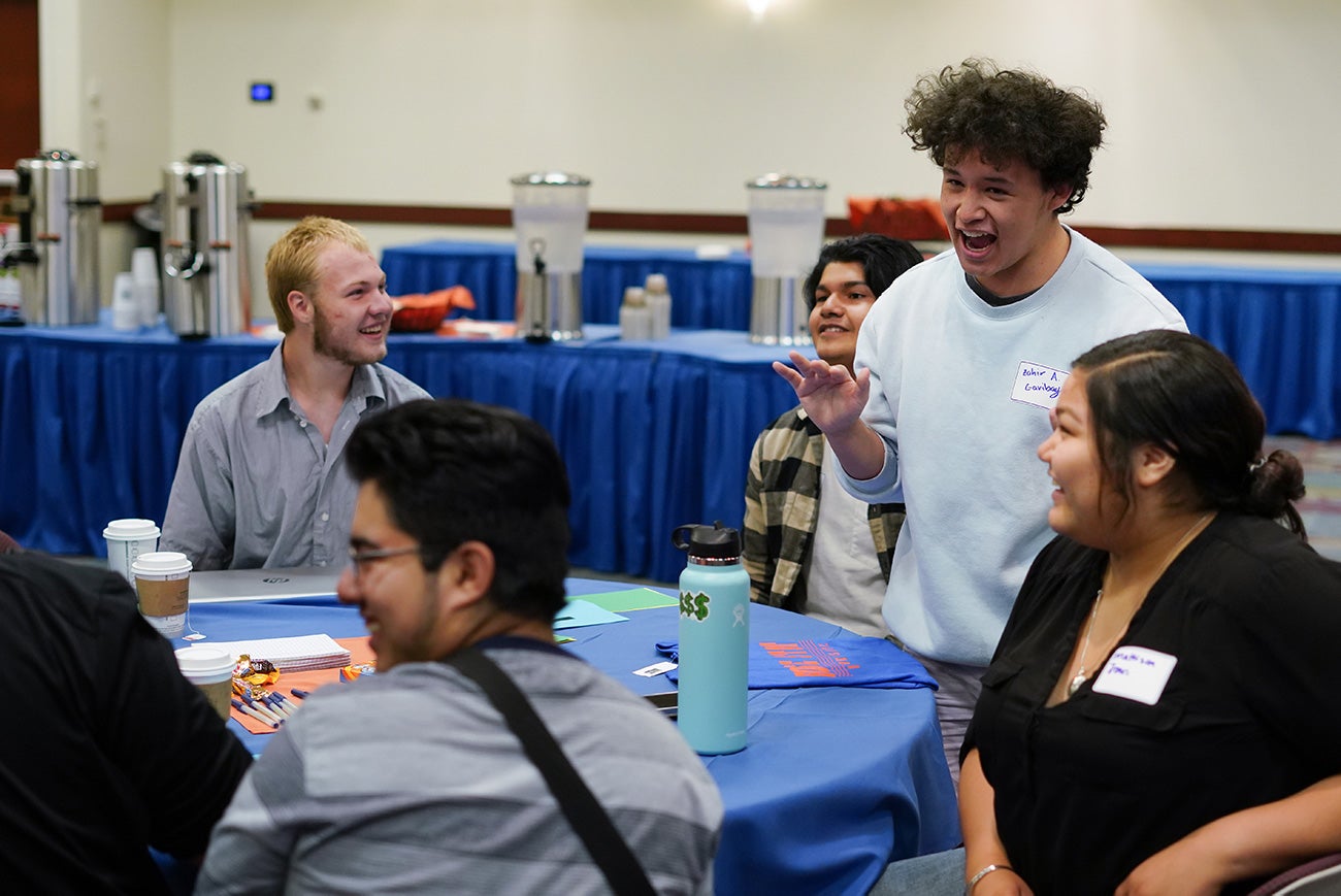 Students sit at a round table, discussing