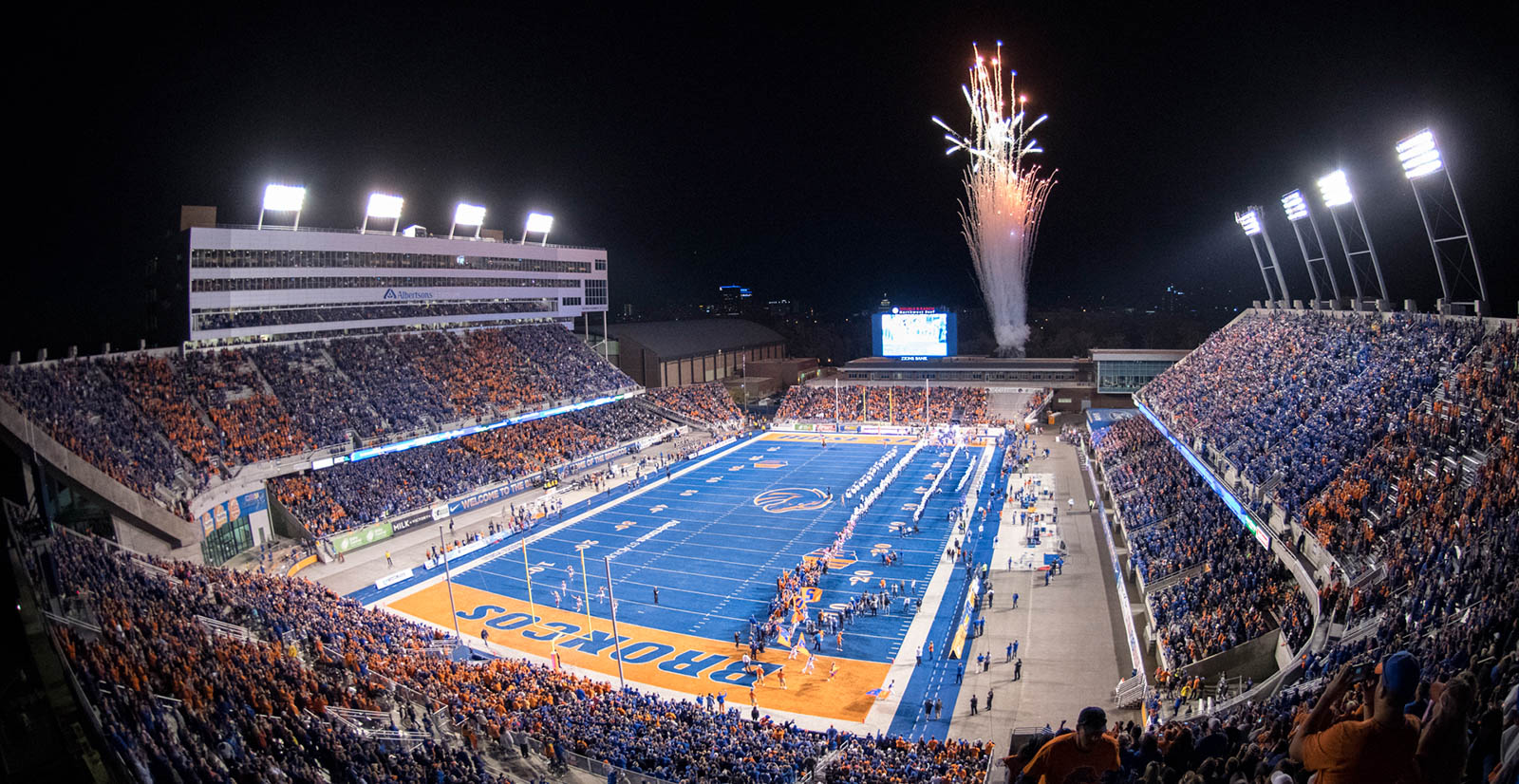 Night lit Albertsons Stadium with students cheering during a Boise State game.