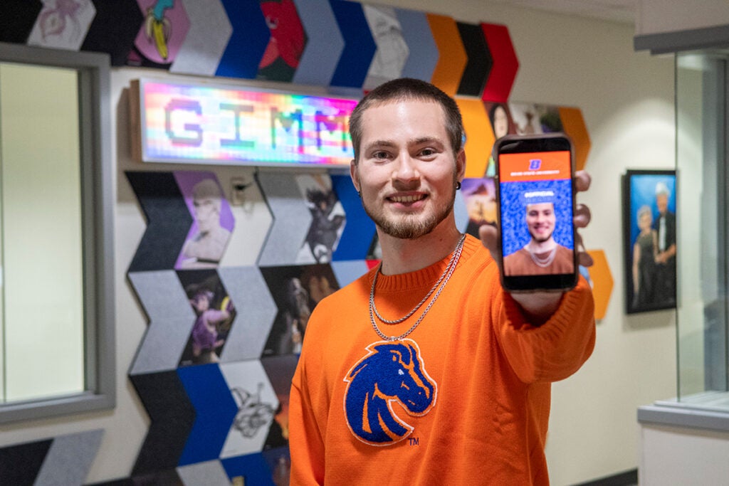 Derek Pyatt holds a phone demonstrating the face filter he created.