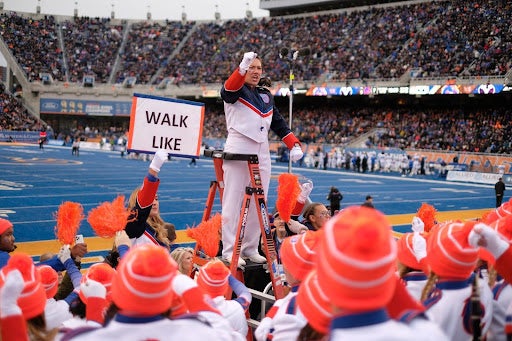 Alsen stands on a ladder addressing band, someone holds a sign that reads Walk Line