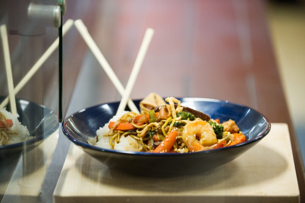 A bowl of stir fry with chopsticks.
