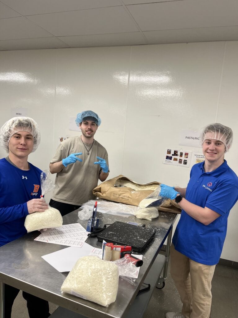 AJ and team mates bag up rice in a kitchen