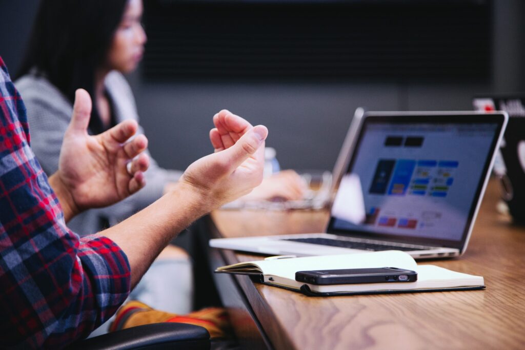 Person gesturing their hands palms up in front of a computer