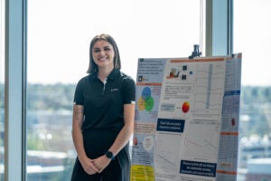 Student stands next to poster presentation