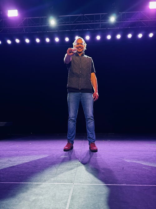 Carlson holds a BOLD pin wup while standing on stage
