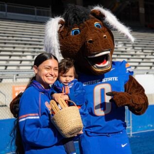 Buster Bronco poses with a woman and baby