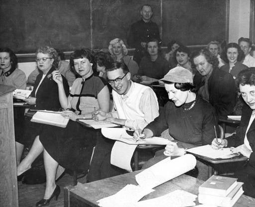 Students smiling at the camera while taking notes