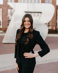 Kate Perkes standing in front of the silver B statue with her hand on her hip, smiling
