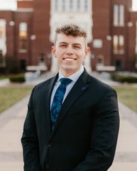 Nick Lloyd in front of brick building smiling