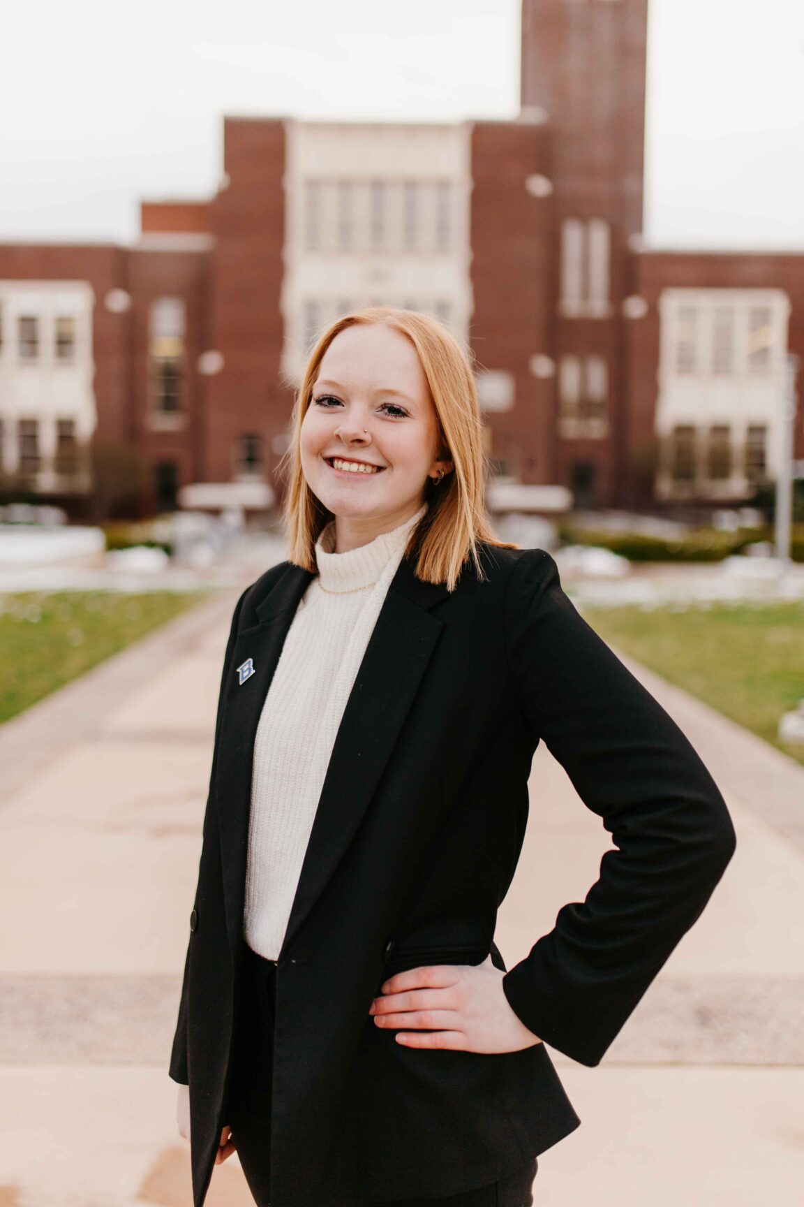 K'Lee Burbank stands in front of a brick building smiling