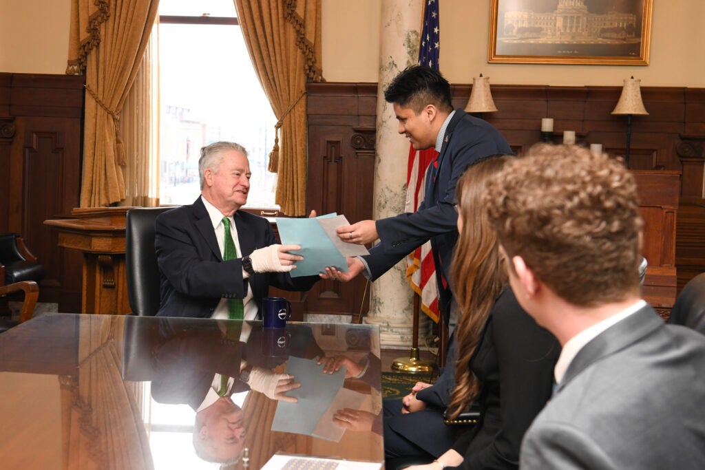Isaac Celedon handing a document to governor Brad Little