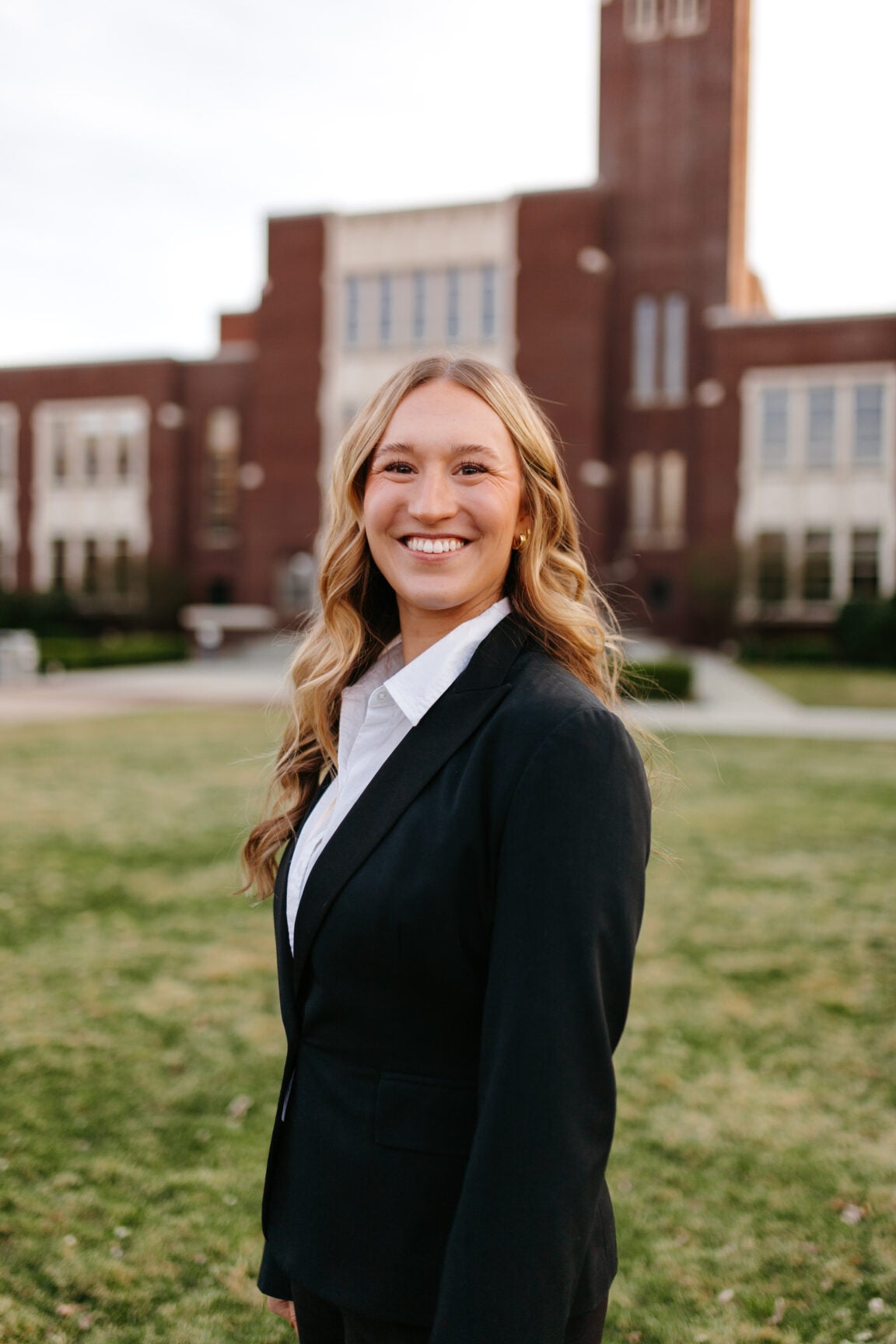 Aubrey Mindlin standing in front of a brick building, smiling