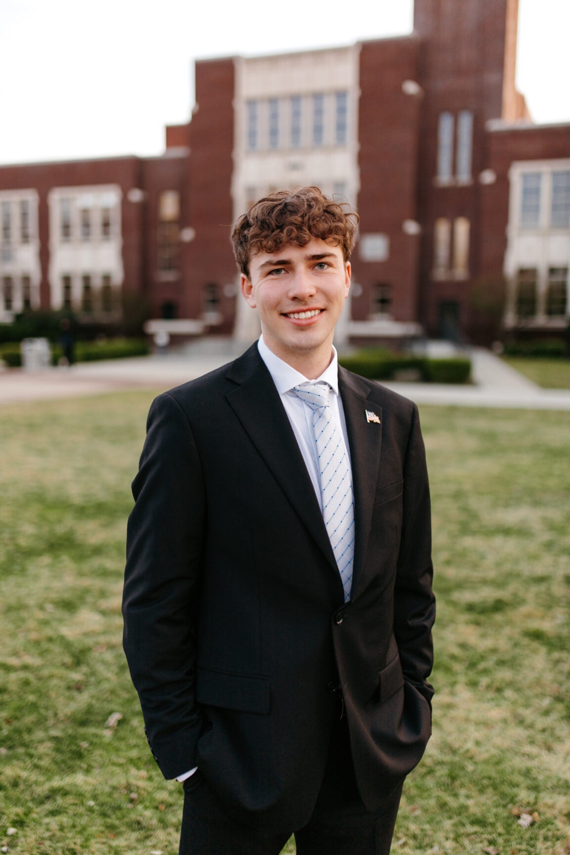 Brady Cooper standing in front of a brick building, smiling