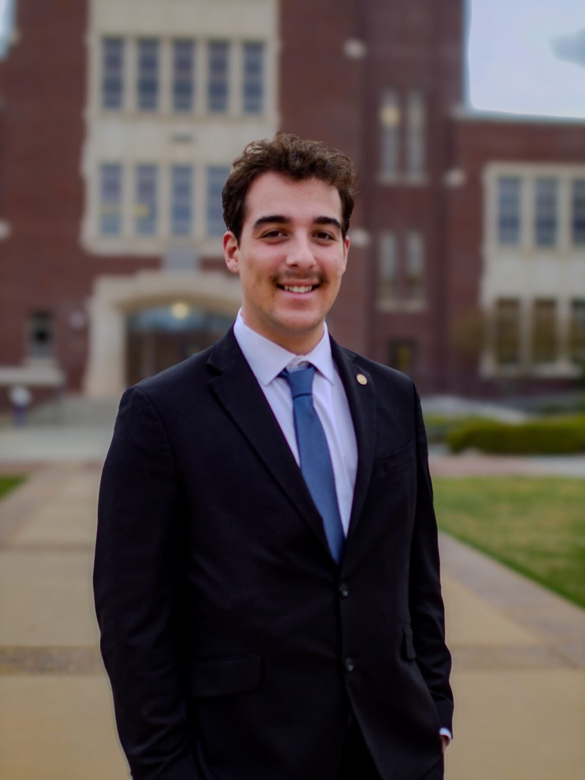 Gavin Verandes standing in front of a brick building, smiling