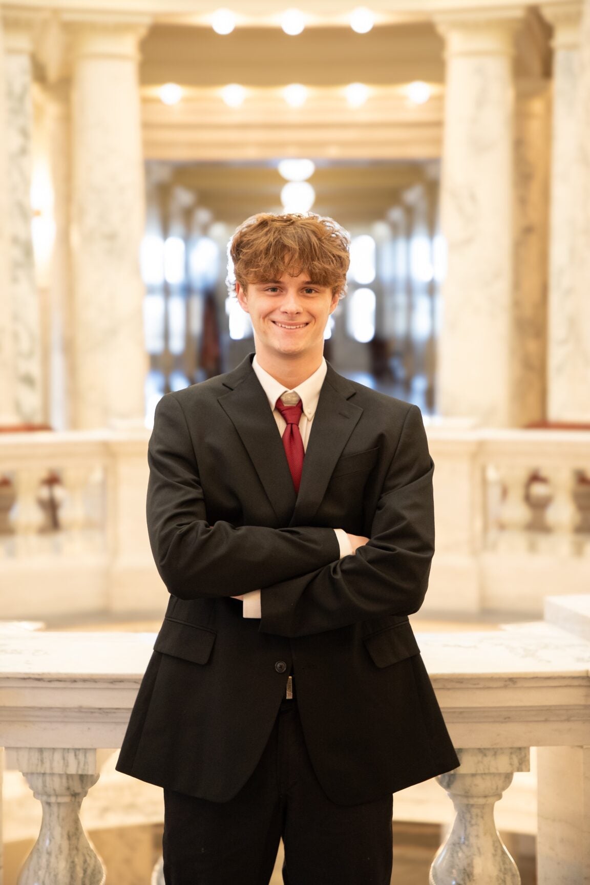 Stephan DeAmbrogio standing in the Idaho state capitol Rotunda, with arms folded and smiling