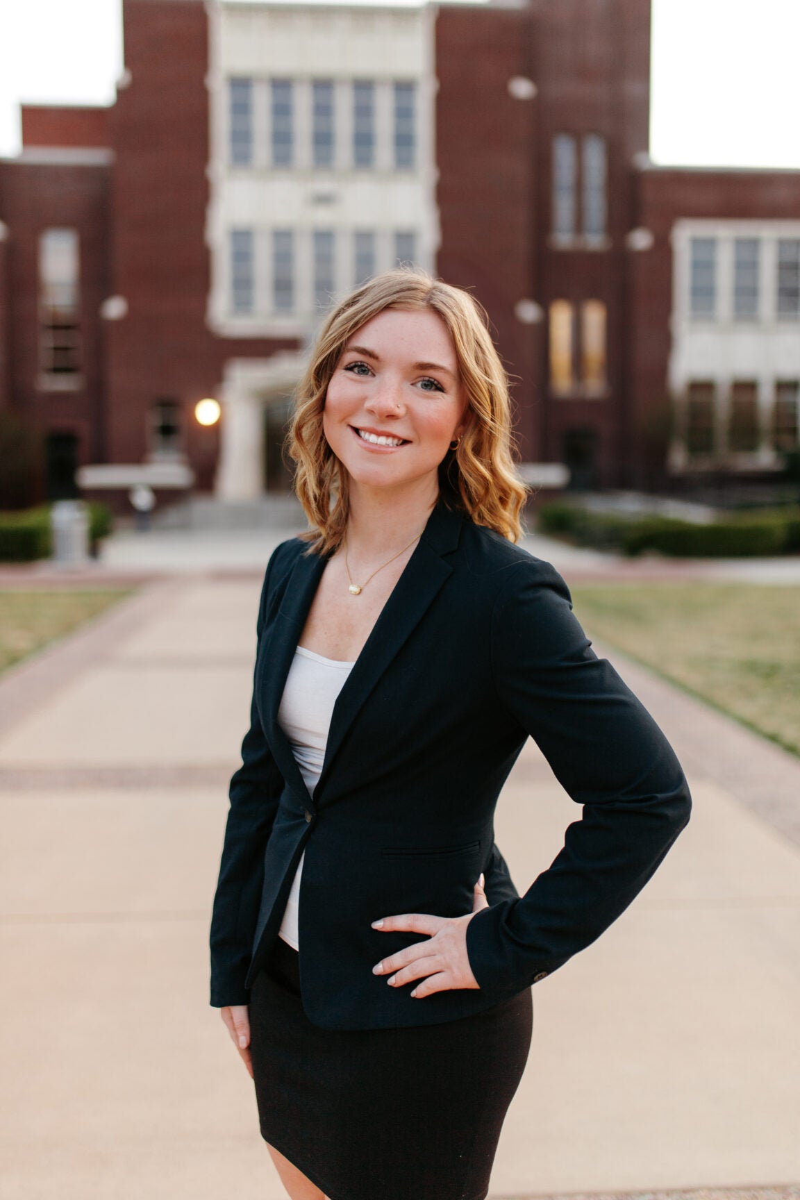 Layne Johnson standing with her hand on her hip and smiling in front of a brick building