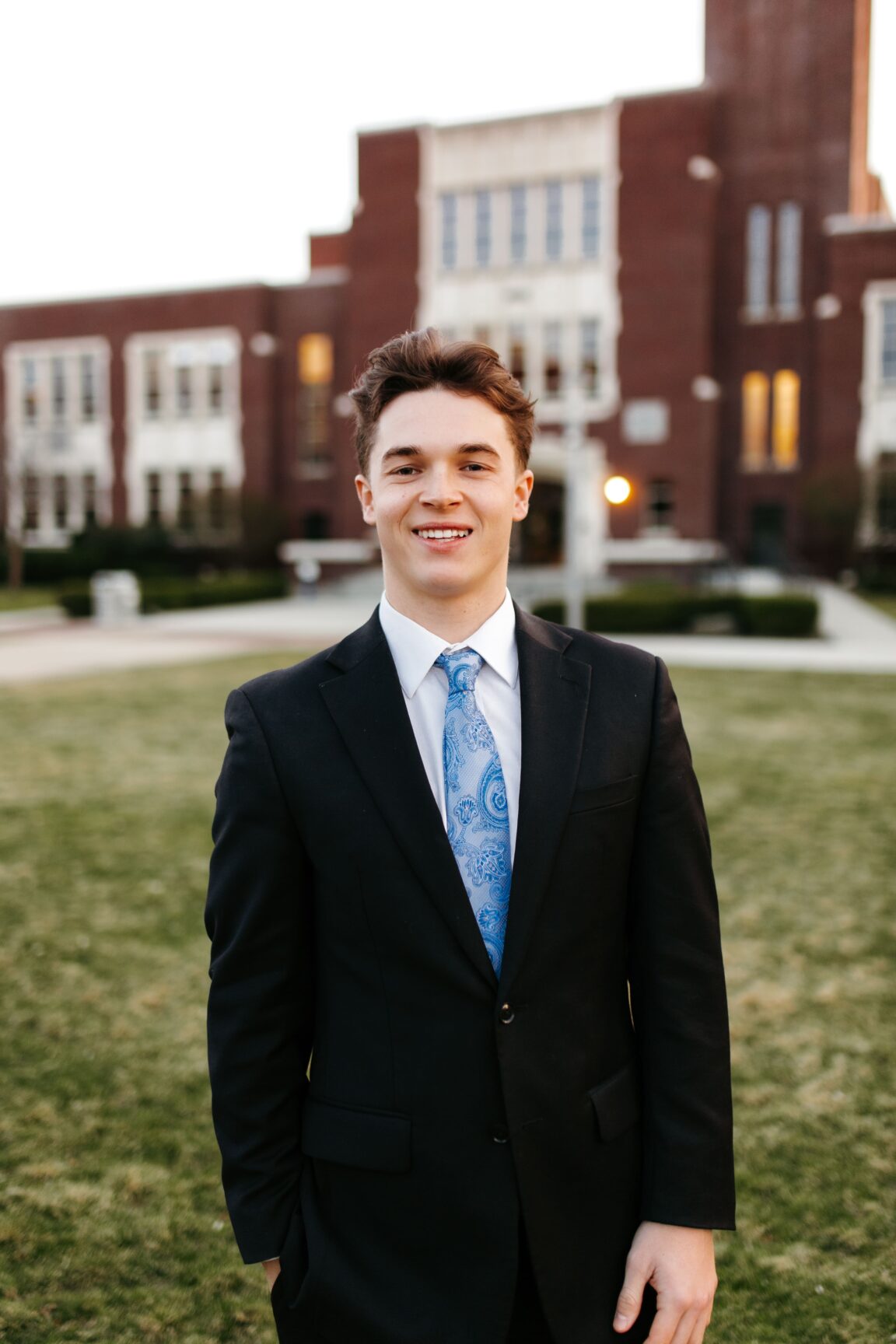 Luca Collins standing in front of a brick building, smiling