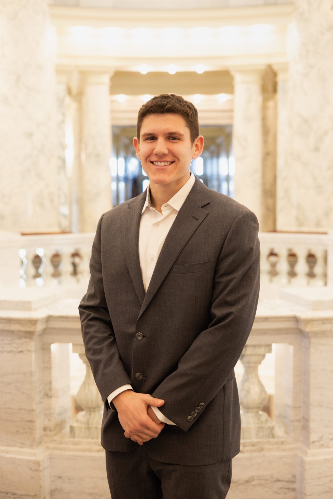 Dominic Mancini standing in the Idaho Capitol Rotunda, smiling with arms folded in front of him