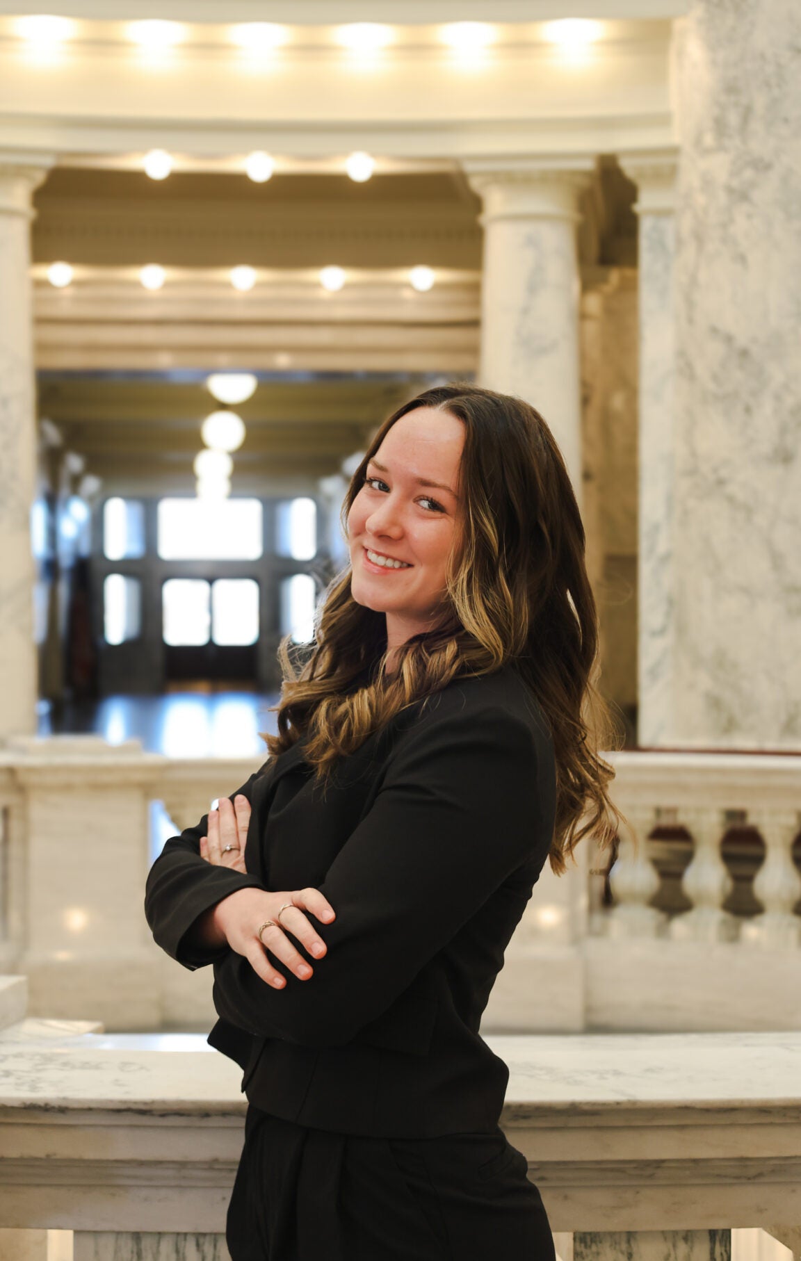 Kaitlyn Matthys standing in the Idaho Capitol Rotunda, smiling and folding her arms