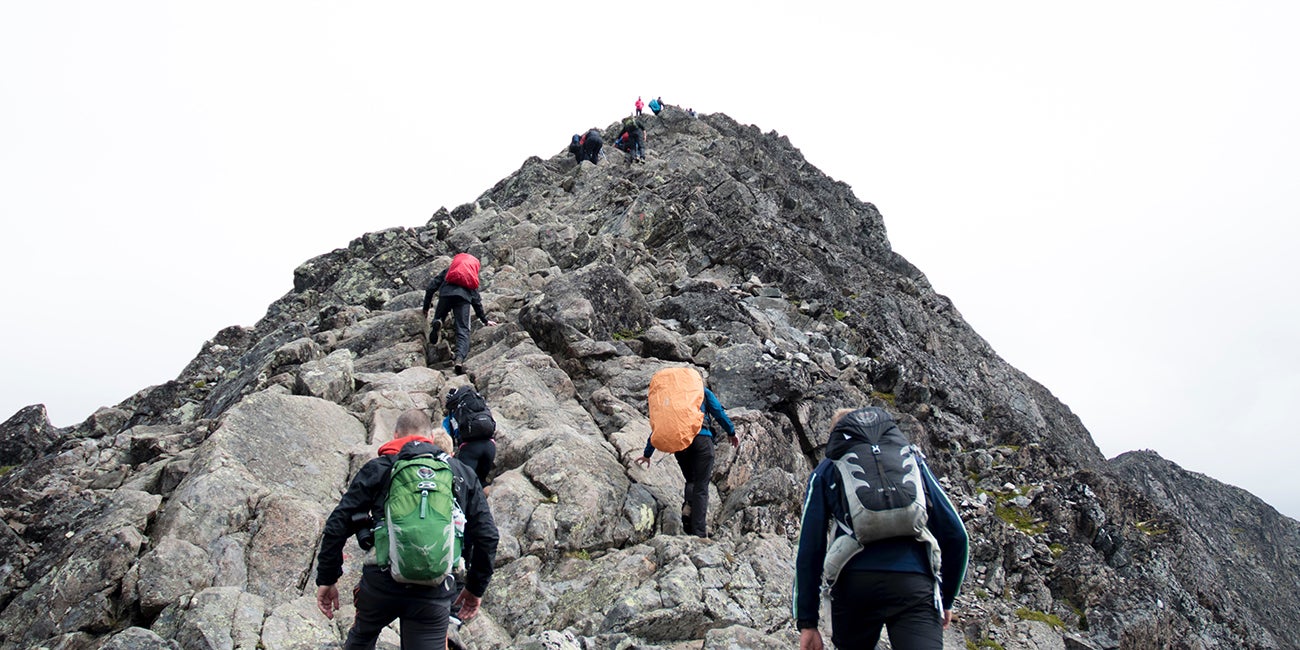 people hiking up a stony mountain peak