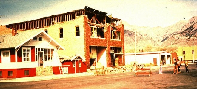 building with damage, people standing behind barriers