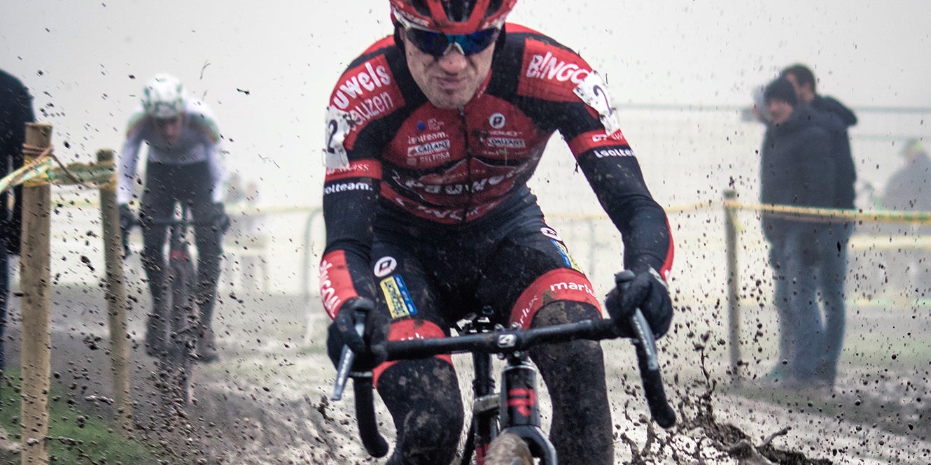 professional riding a bike through a mud puddle