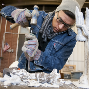 A man using a chisel to build a sculpture