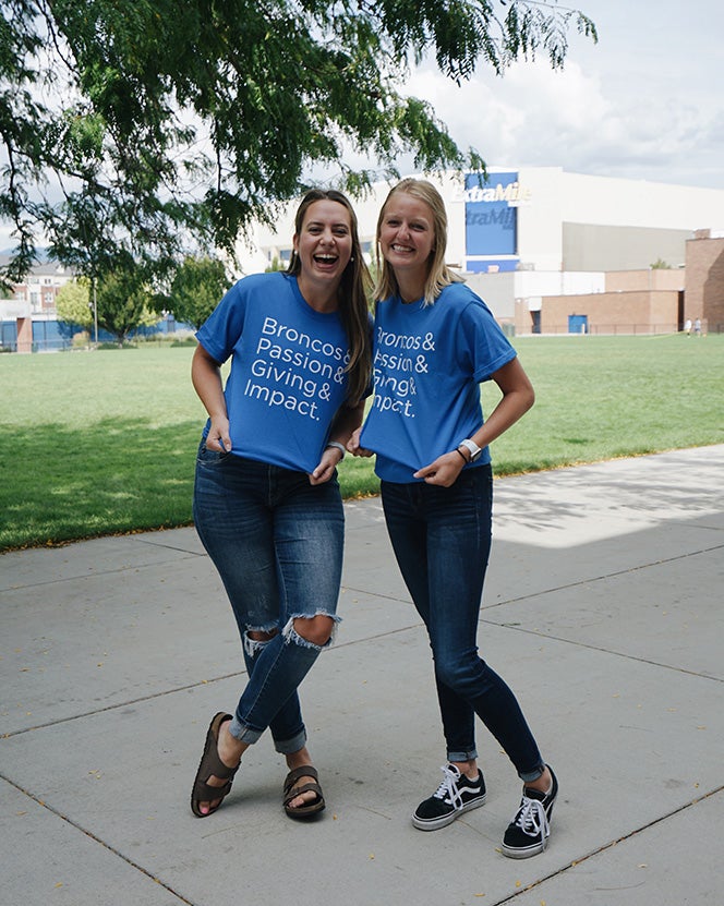 Sadie and Kristen wearing shirts that say Bronco and passion and giving and impact