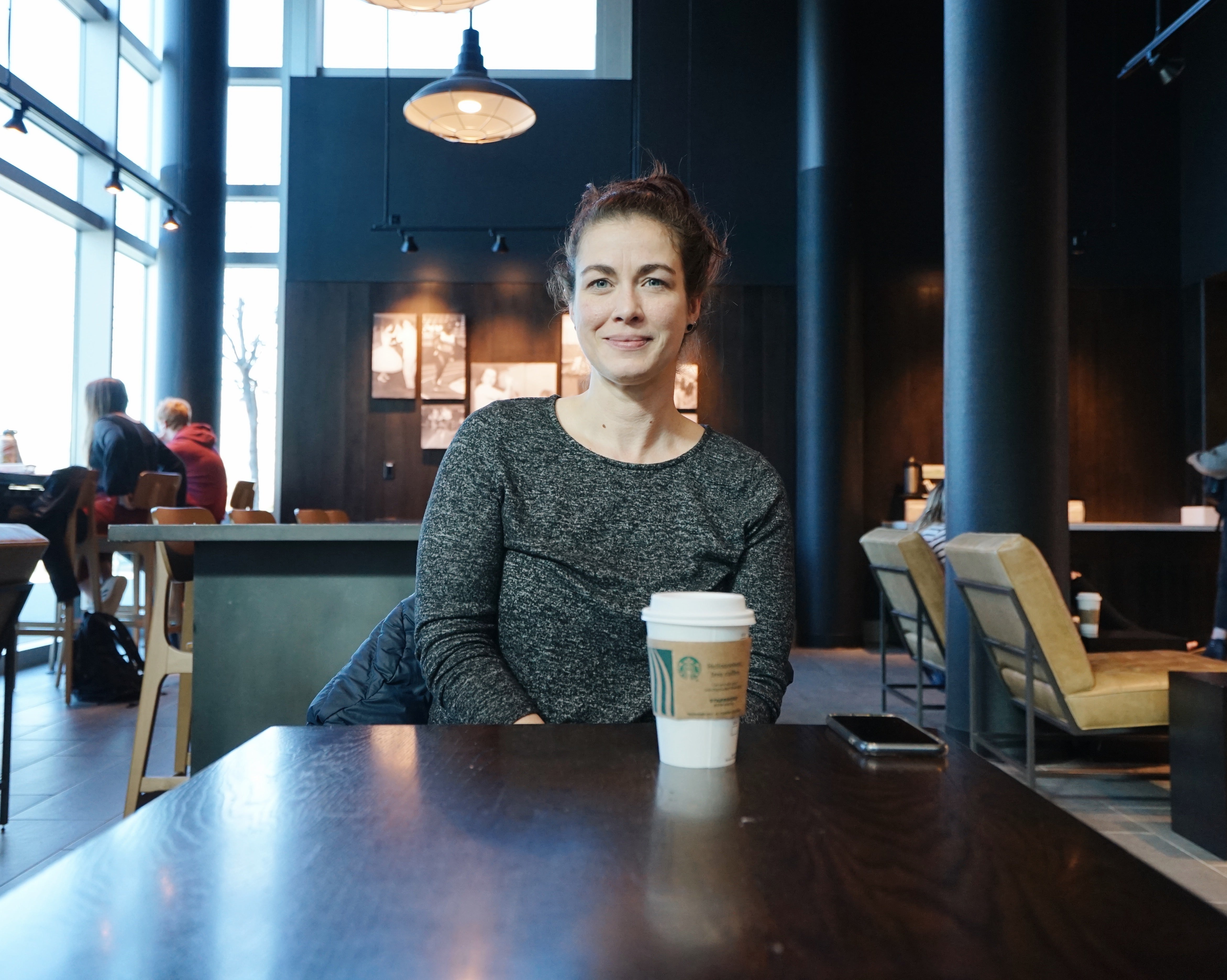 Andrea smiling at the camera, sitting at the Starbucks in the Boise State SUB