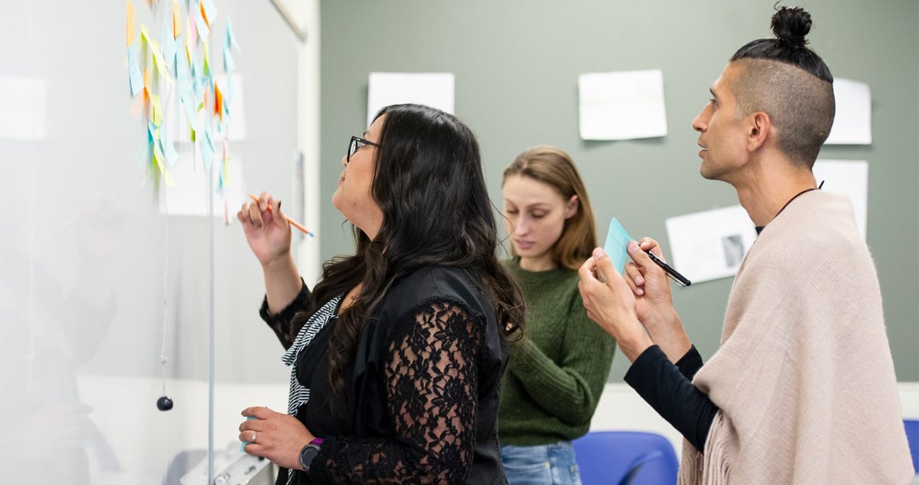 Two women and one man User Experience Research Certificate program students at Boise State working together at a whiteboard