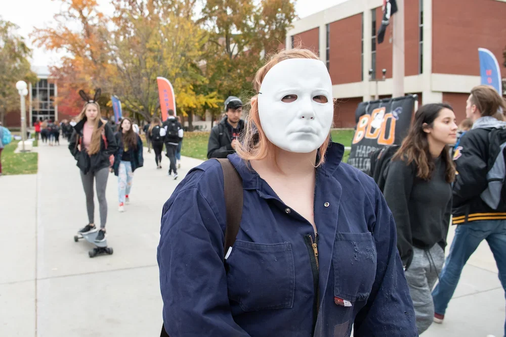 Student on campus wearing a Halloween mask,