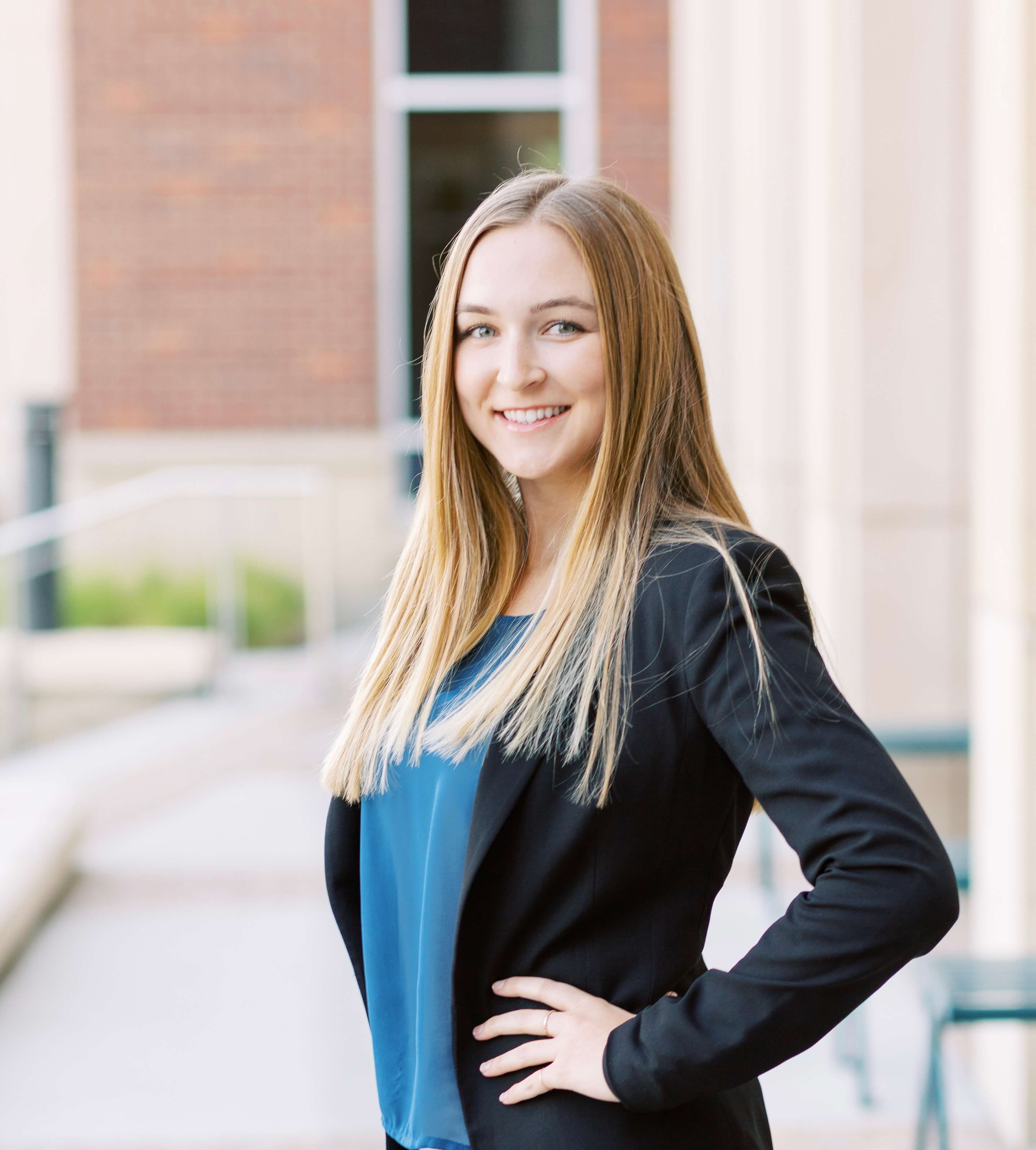 Sarah wearing a black blazer and posing in courtyard