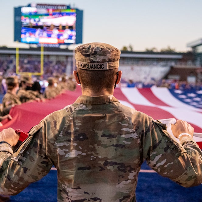 Student dressed in military uniform holding an American flag 