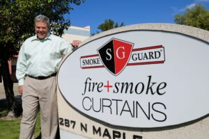 Gonzales standing near Smoke Guard business sign