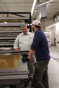 Gonzales talking with person in a warehouse