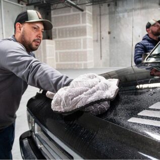 Gabe Garcia, with The Rag Company, wipes down the hood of a pickup truck