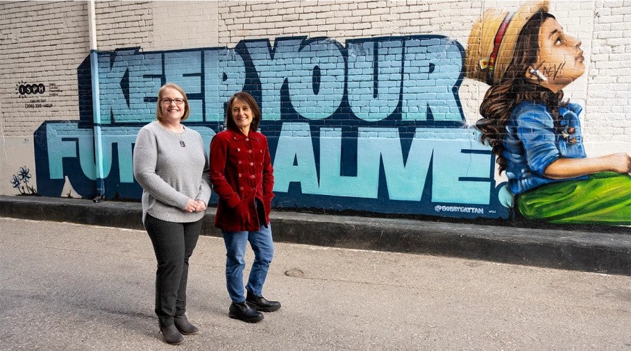 EMBA students pose in front of mural