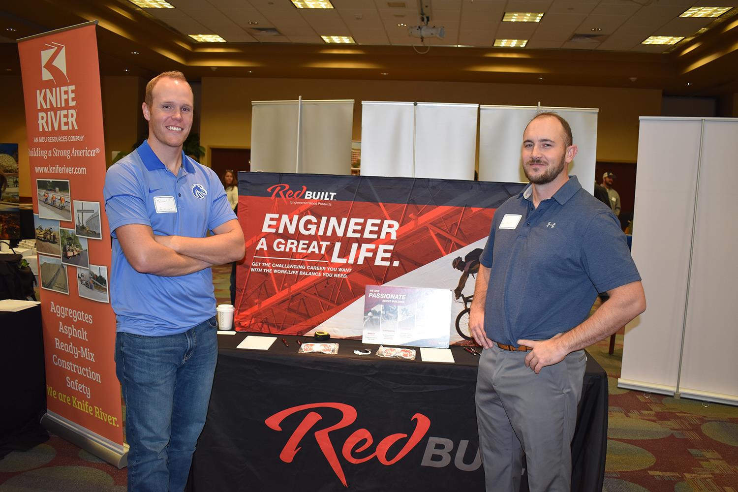 2 people standing next to a table at a career fair