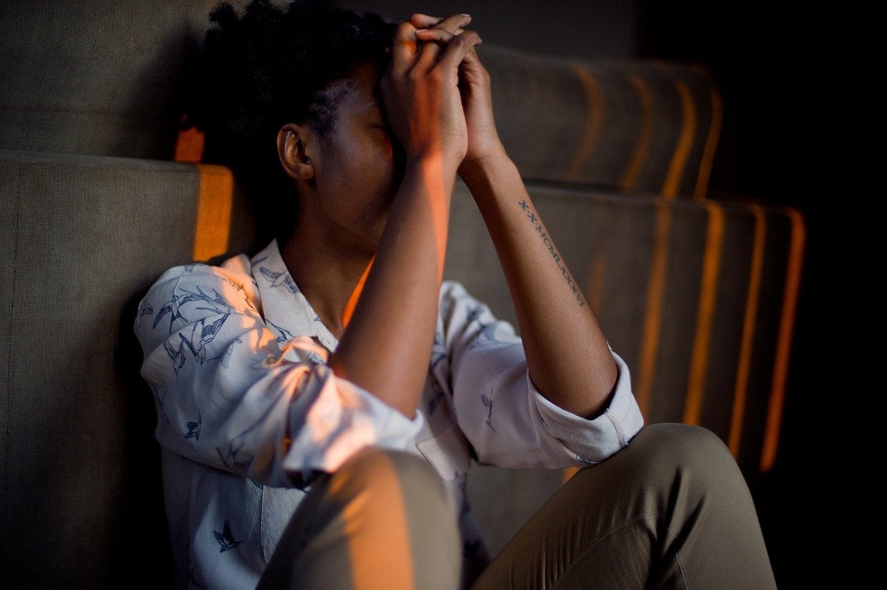 a woman sitting on the floor with hands in front of her face