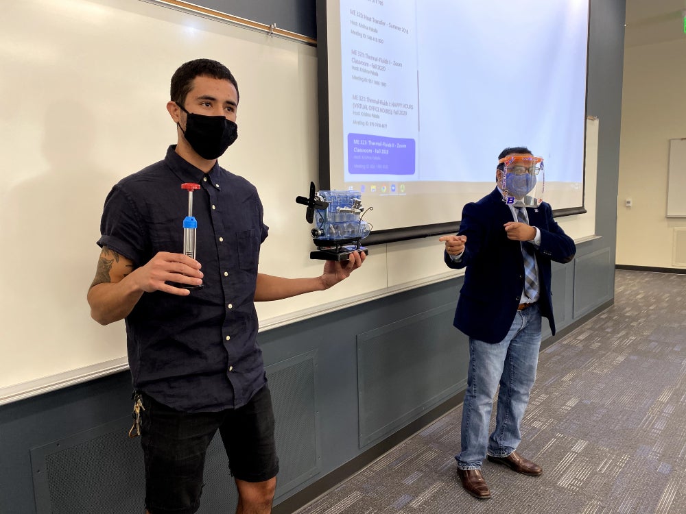student displaying engineering example in front of classroom