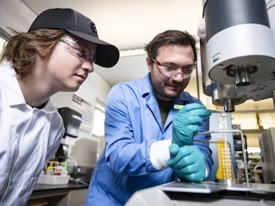 Two materials science students working in a lab with equipment