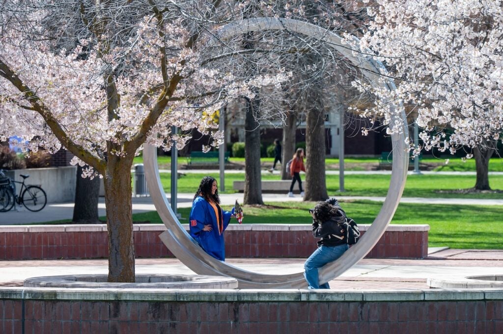 A photographer photographs a graduate in regalia
