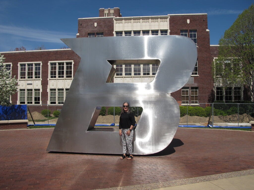 Marta standing in front of B statue in front of admin building