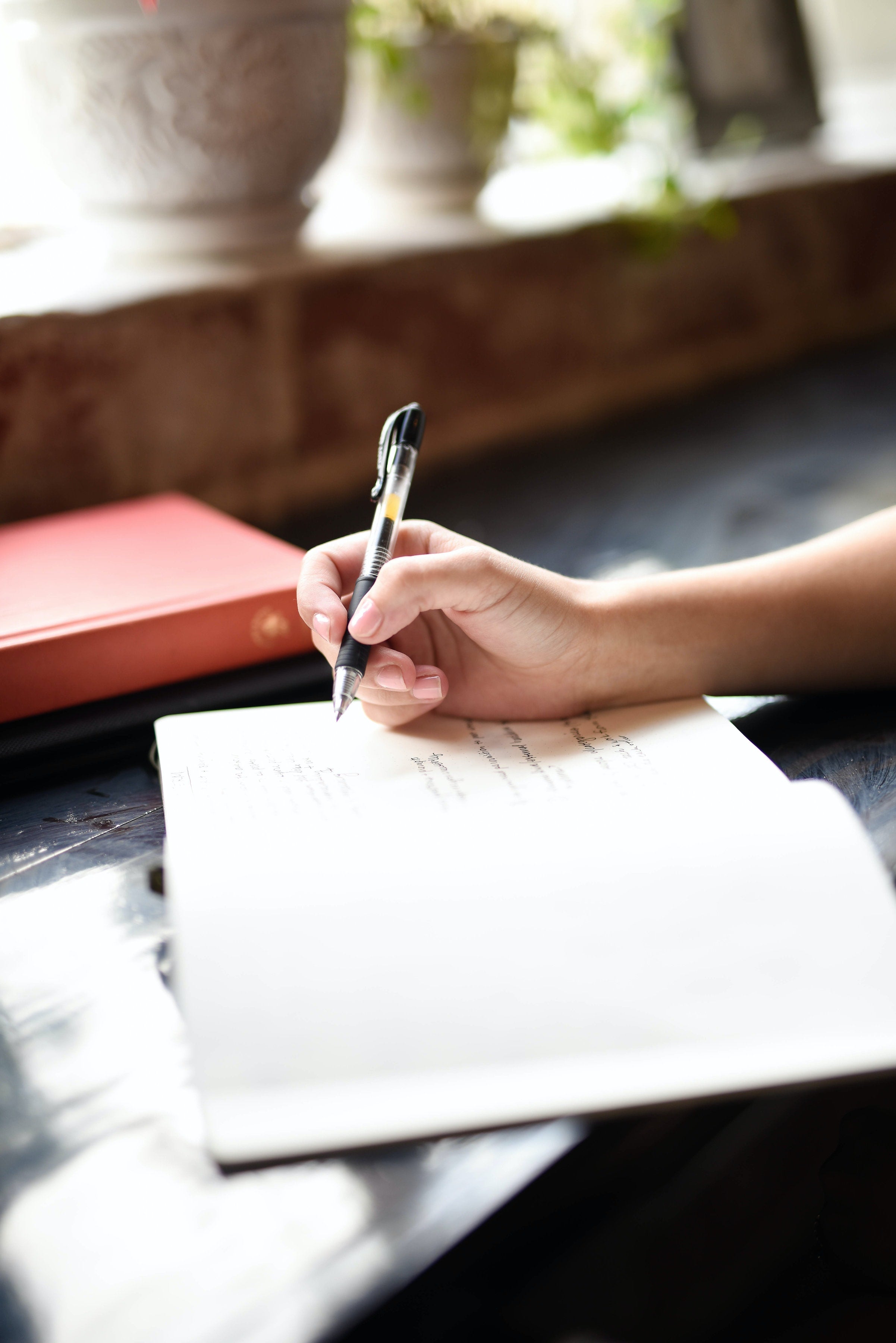 Hand writes in journal resting on table