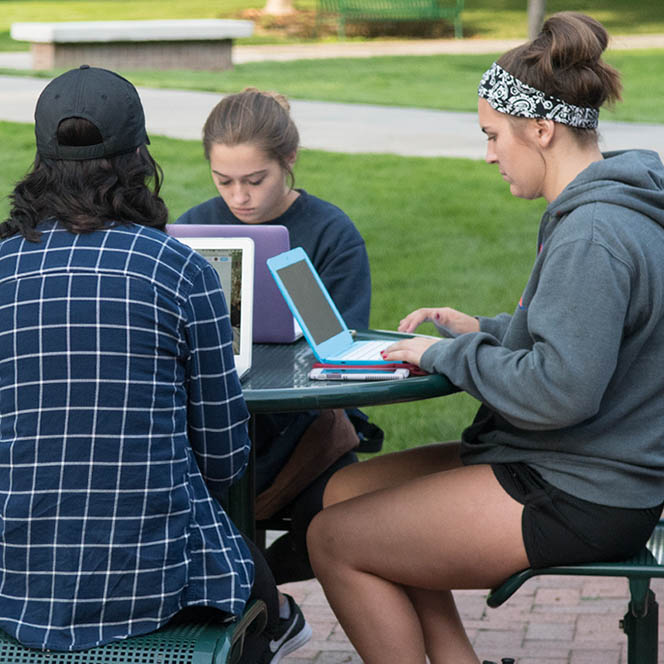 Students work on laptops outside 