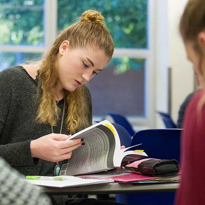 Student reading textbook at desk
