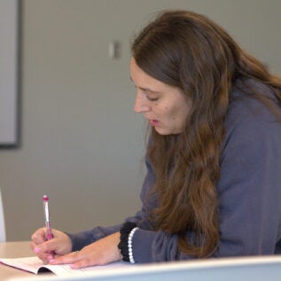 Faculty member writes notes from a workshop