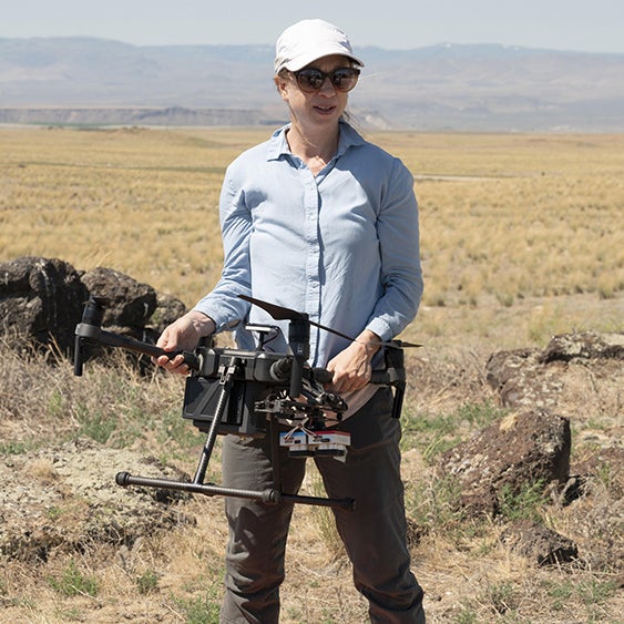 Dr. Megan Cattau holds a drone in the desert.