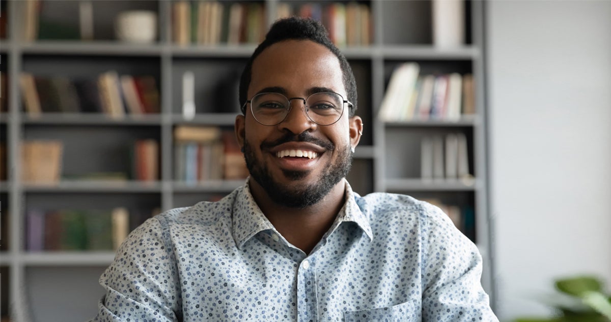 A man wearing glasses smiles.